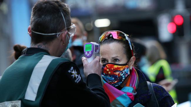 A St John Ambulance staffer takes the temperature of a client arriving at a Sydney vaccination centre in July. Picture: Getty