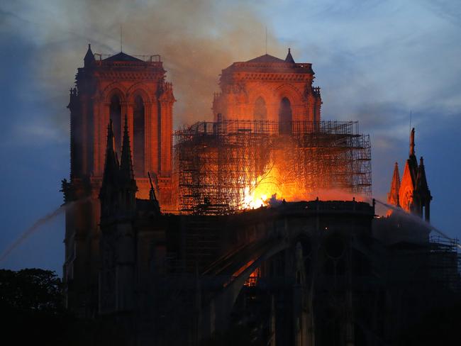 Firefighters tackle the blaze as flames and smoke rise from Notre Dame cathedral as it burns in Paris, Monday, April 15, 2019. Massive plumes of yellow brown smoke is filling the air above Notre Dame Cathedral and ash is falling on tourists and others around the island that marks the center of Paris. (AP Photo/Michel Euler)