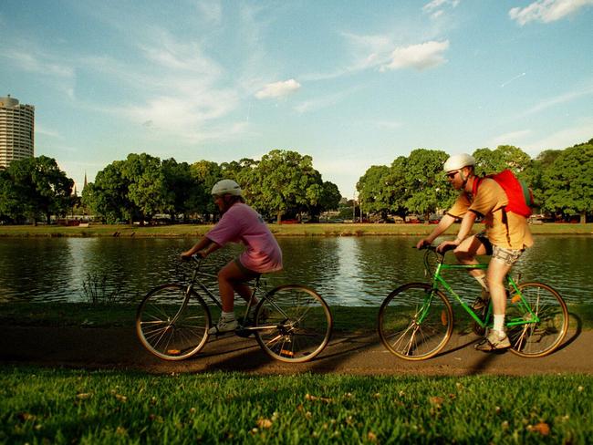 People riding their bicycles along the banks of the Yarra River.