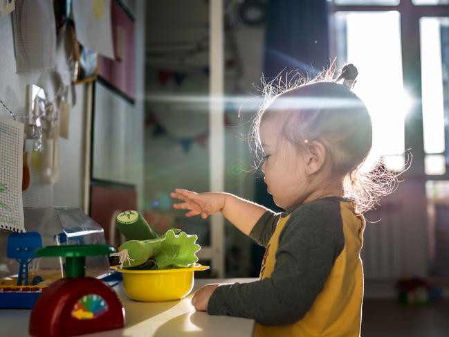 A little girl plays in her room with scales and vegetables.