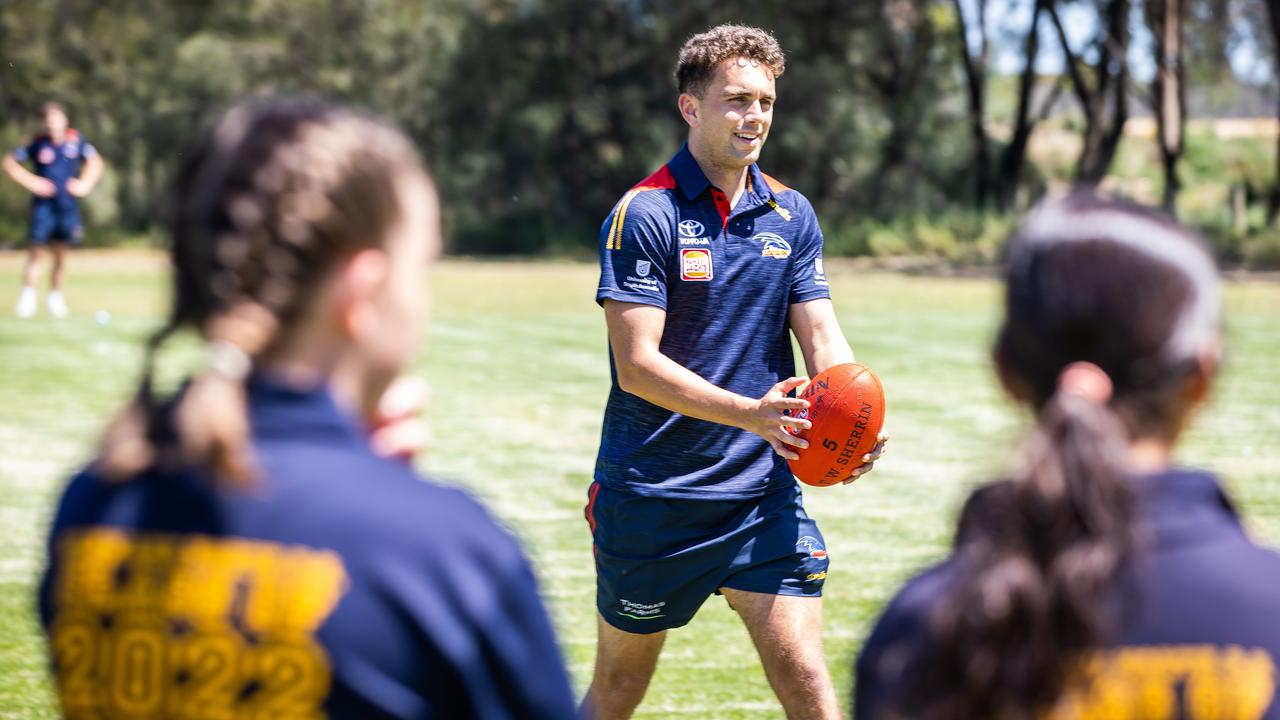 Crow Lachlan Sholl kicks the footy with students from Renmark High. Picture: Tom Huntley