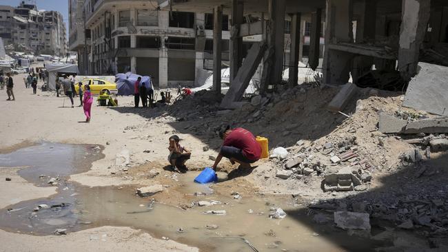 Two Palestinian children scoop water from a muddy puddle caused by a broken pipe in Gaza City on Saturday. AP Photo/Jehad Alshrafi