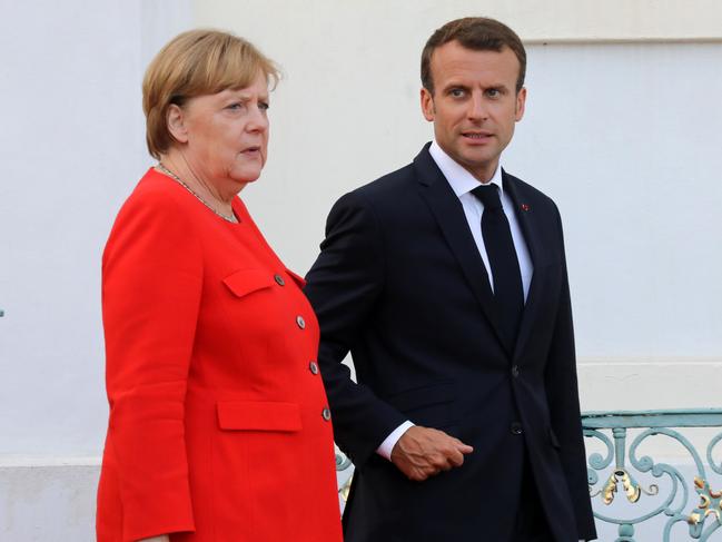 German Chancellor Angela Merkel (L) and French President Emmanuel Macron arrive to welcome EU Commission President Jean-Claude Juncker upon his arrival for a meeting on June 19, 2018, at the Meseberg Palace, northeastern Germany, ahead of a EU summit to be held on June 28-29. / AFP PHOTO / Ludovic MARIN