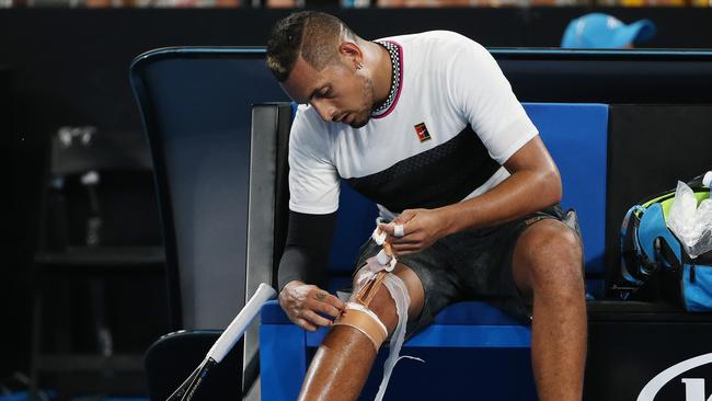 Nick Kyrgios removes the tape of his knee in the third set. Picture: Michael Klein