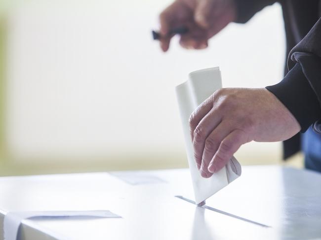 Hand of a person casting a ballot at a polling station during voting. election voting vote polling poll generic Townsville