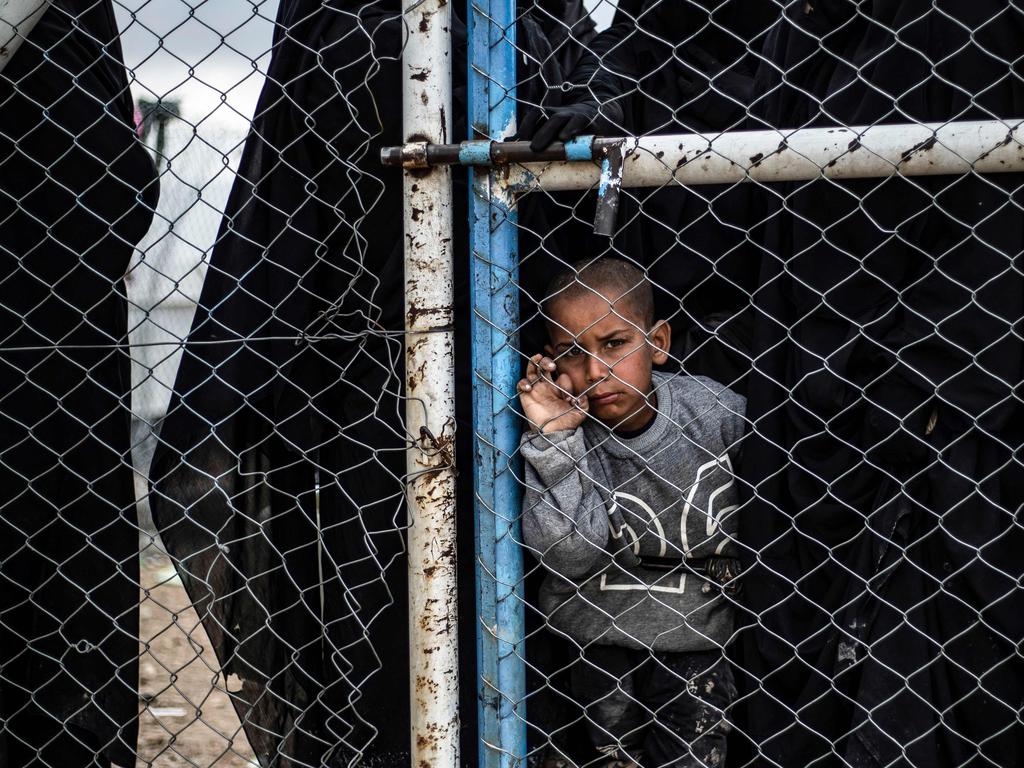 A child waits behind a wire fence door in al-Hawl camp. Picture: Delil Souleiman/AFP