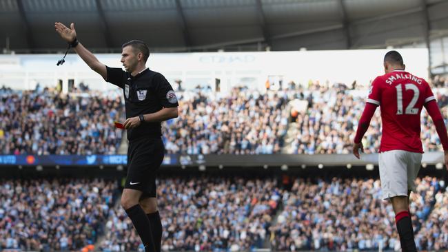 Manchester United's Chris Smalling, right, is shown a red card by referee Michael Oliver during their English Premier League soccer match against Manchester City at the Etihad Stadium, Manchester, England, Sunday Nov. 2, 2014. (AP Photo/Jon Super)