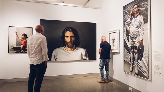 Visitors viewing the portrait of Behrouz Boochani by artist Angus McDonald.