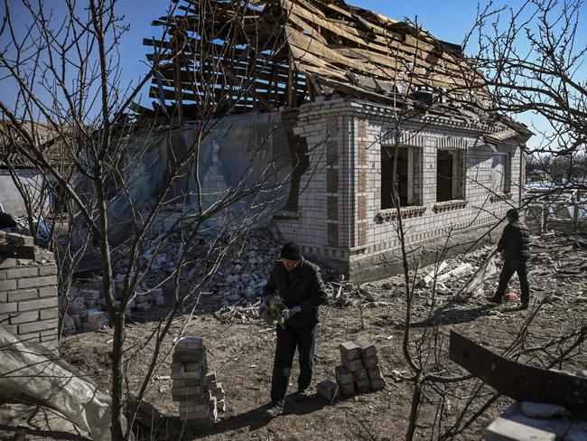 People clean up the debris from destroyed houses after bombardments in Krasylivka. Picture: AFP