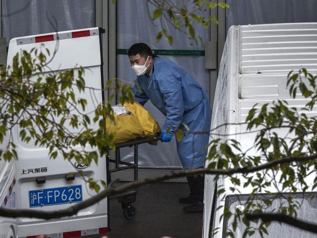 SHANGHAI, CHINA - JANUARY 13: (CHINA AND HONG KONG-OUT) Funeral workers load bodies into vans to be taken for cremation at a busy local funeral home on January 13, 2023 in Shanghai, China.Chinas health care system has been struggling to cope with a surge of COVID-19 infections since the government ended nearly three years of tough zero COVID controls. At least 900 million people have been infected, according to a Peking University study, and authorities have reported 60,000 COVID-related deaths in hospitals alone in the past month. Infections have peaked in major cities including Beijing and Shanghai, but a second wave is expected to hit in rural areas with hundreds of millions of people traveling to their hometowns during the Lunar New Year holiday. Health officials are concerned that rural populations tend to be older, and the medical system in smaller towns and villages are not as well-resourced as bigger cities.(Photo by Kevin Frayer/Getty Images)