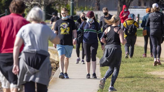 A man walks with his mask on his chin at Albert Park Lake. Picture: Wayne Taylor