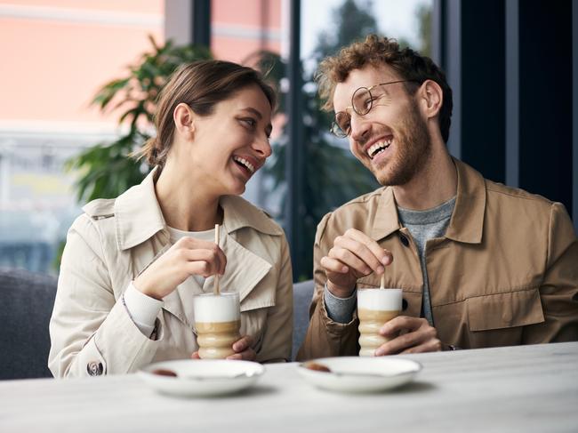 Young couple is enjoying a fun date at their local coffee shop, laughing and drinking coffee together