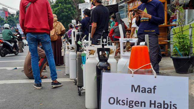 Signage that reads ‘sorry, out of oxygen’ is seen as people queue outside an oxygen refilling shop to fill tanks for sick family members in Jakarta. Picture: AFP