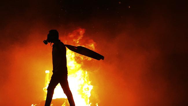 A Palestinian protester walks by a burning tyre amid clashes with Israeli security forces at the Hawara checkpoint, south of Nablus city, in the occupied West Bank. Picture: AFP