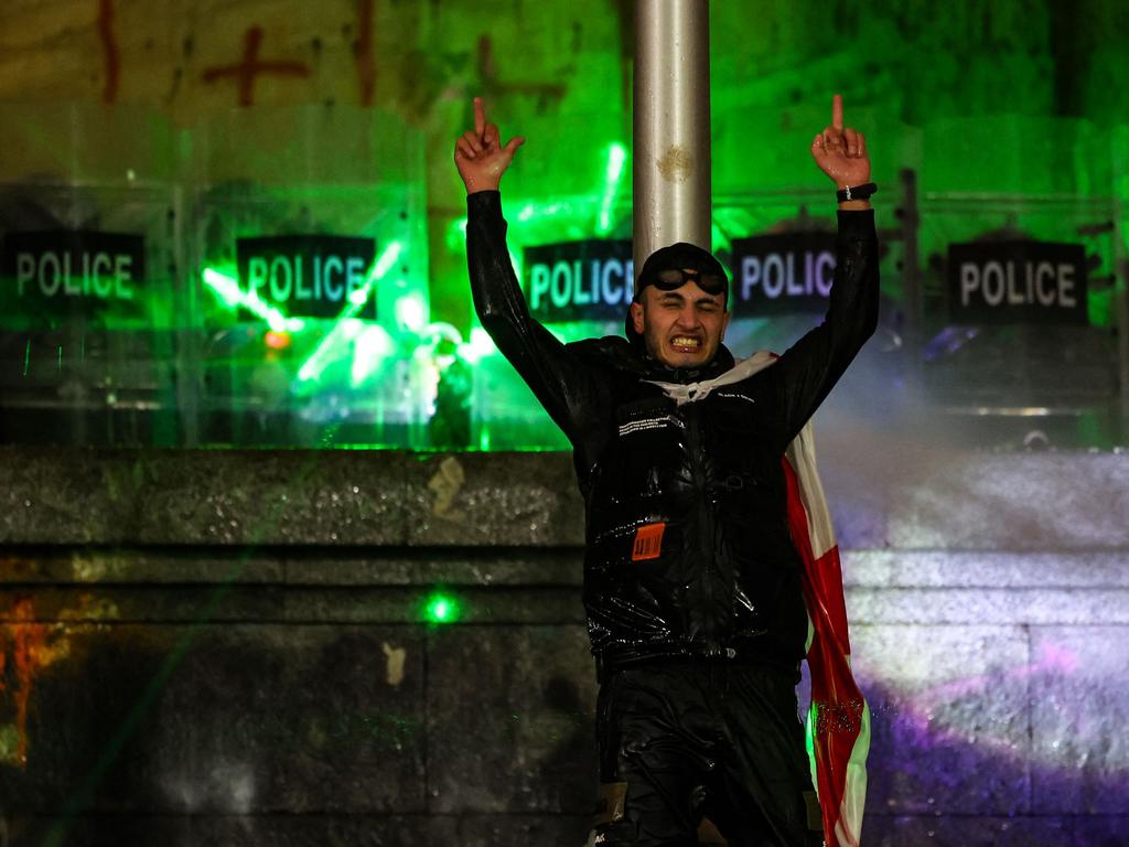 A protester is seen gesturing to the line of police forming a shield wall behind him. Picture: Giorgi ARJEVANIDZE / AFP