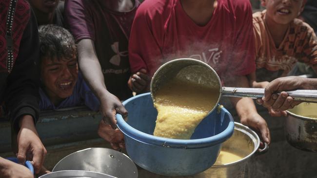 Palestinian children struggle to get donated food at a community kitchen last month in Khan Younis, southern Gaza Strip. Picture: AP /Abdel Kareem Hana