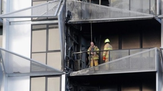 Firefighters check through the building after the fire spread quickly through the cladding.