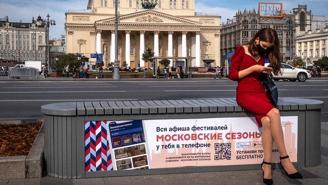 A woman wearing a face mask sits on a bench near the Bolshoi theatre (background) in downtown Moscow. Picture: AFP