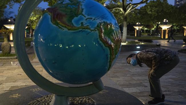 A resident wearing a mask against the coronavirus looks at a giant globe in Wuhan in central China's Hubei province on Monday. Picture: Ng Han Guan/AP