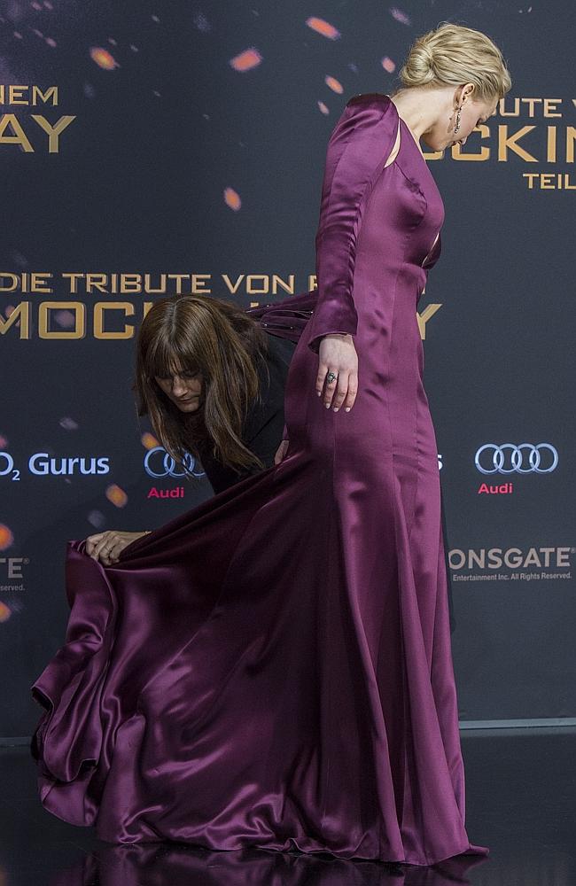 An assistant rearranges Jennifer Lawrence’s dress at the world premiere of the film ‘The Hunger Games: Mockingjay - Part 2’ on November 4, 2015 in Berlin. Picture: AFP