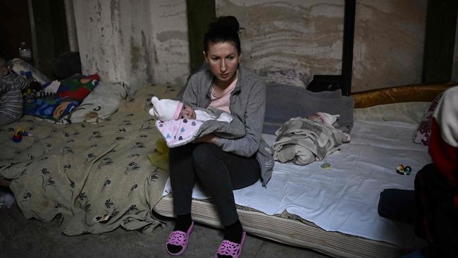 A woman sits with two babies being treated at a paediatrics hospital after they were moved to the basement. Picture: Aris Messinis / AFP