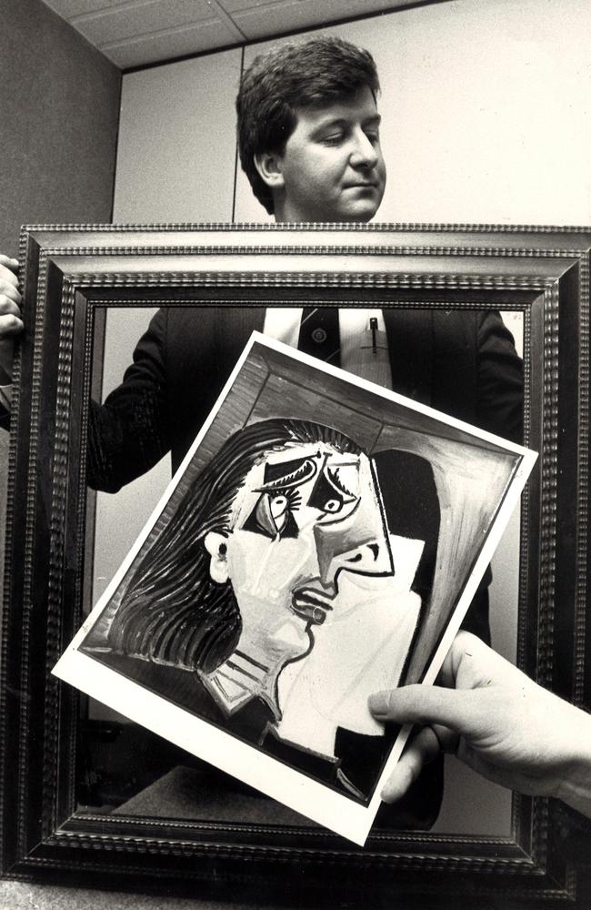 1A photo of the Picasso painting stolen from the National Gallery of Victoria is held before the empty frame being examined by Sen-Det Tony Jay.