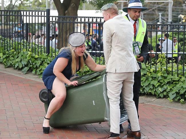 The girl in blue and her beige-suited friend start horsing around on the back of a wheelie bin. Picture: Getty.