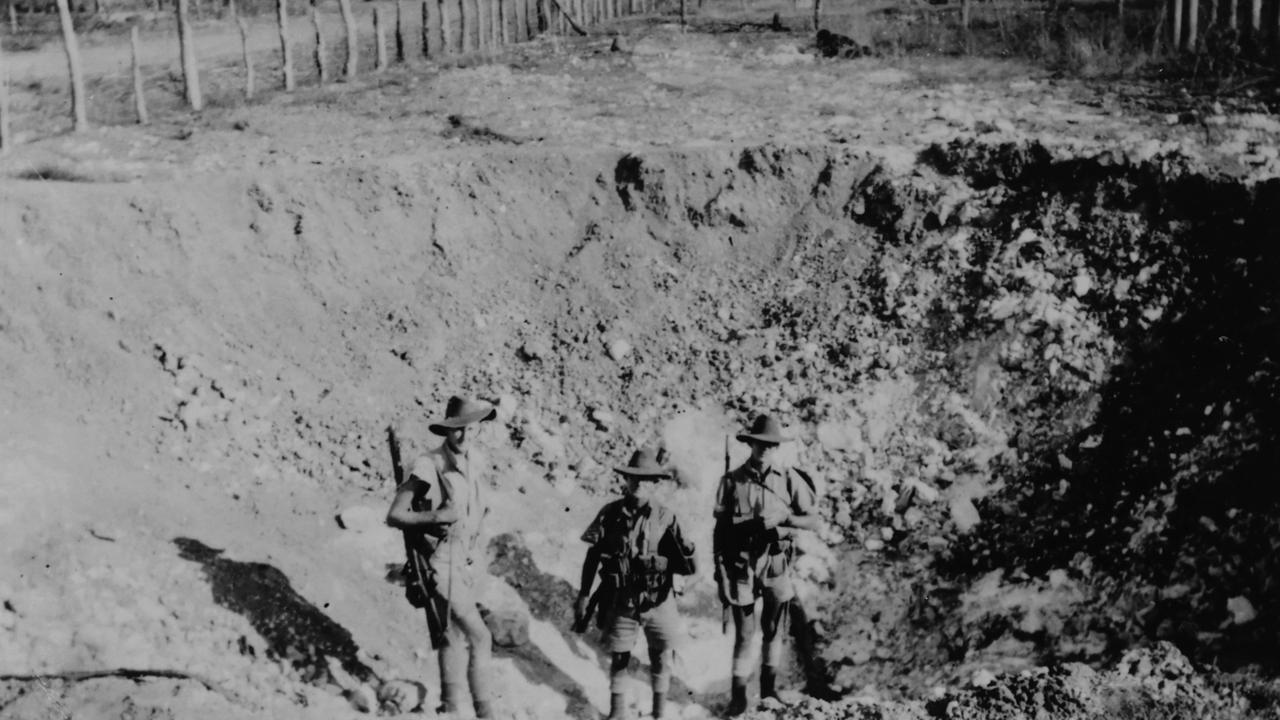 Fellow soldiers stand in the crater of the first bomb felled on Darwin on February 19, 1942. Picture Basil Stahl/Supplied