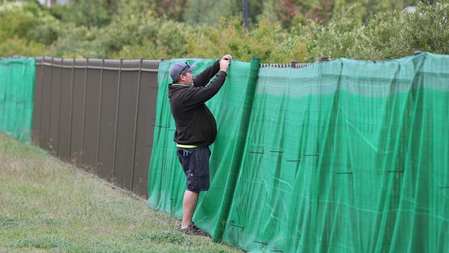 A man attaches screening around Newmarch House in western Sydney on Tuesday. Picture: Richard Dobson