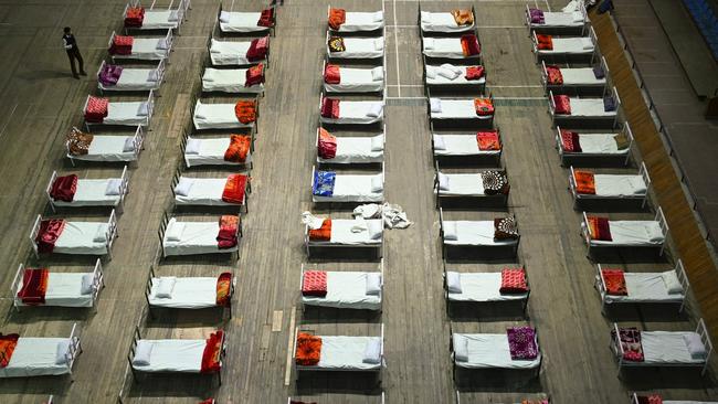 A worker stands next to beds during preparations to convert an indoor stadium into a Covid-19 coronavirus centre in Srinagar.