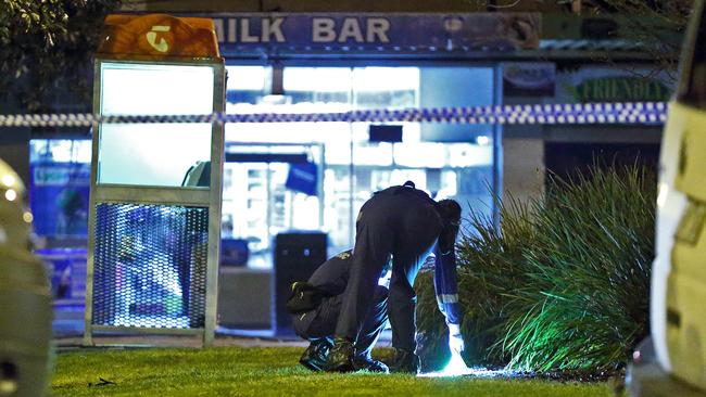 A forensic officer places an evidence marker outside the Doveton milk bar where Mr Husseini was killed. Picture: Patrick Herve