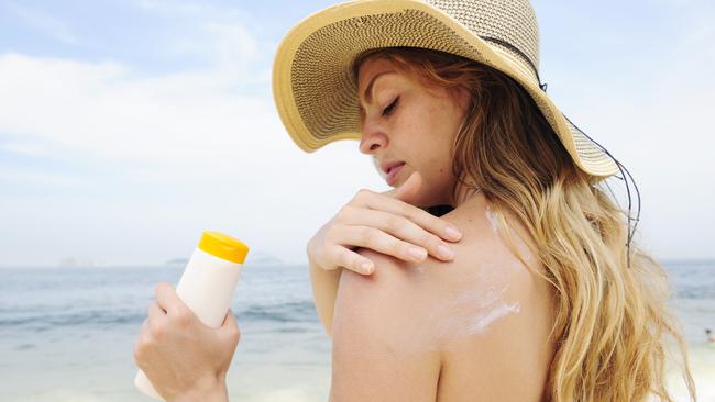 woman applying suntan lotion at the beach smiling