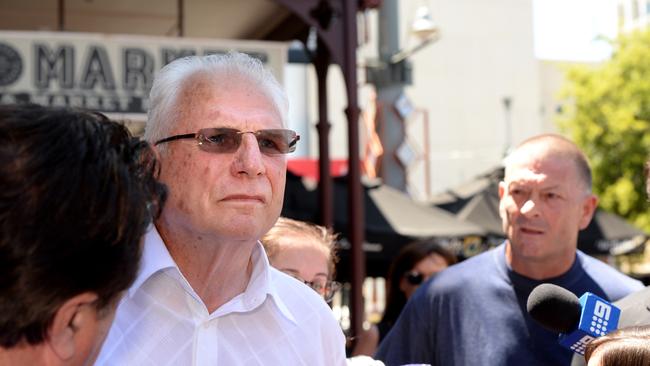 Robert Wayne Collins (centre), half of a couple being sued in the District Court for allegedly defrauding people through a real estate scheme confronted by one of his victims Colin Preston (right) outside court.