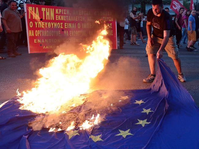 An anti-EU protester burns an EU flag outside the European Commission offices in Athens. Picture: Louisa Gouliamaki