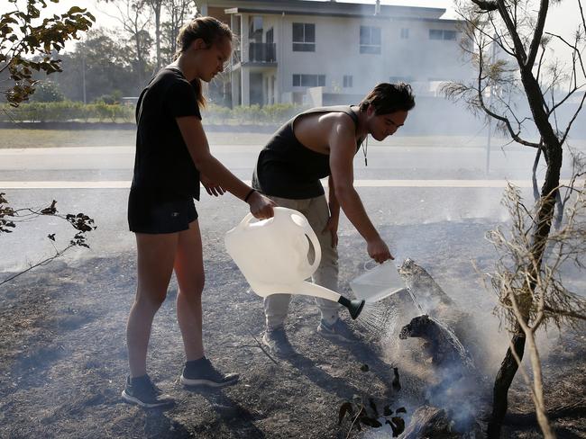 Brooke and Tristan Smith blacken out bush near their home at Wallabi Point on Saturday. Picture: AAP/Darren Pateman