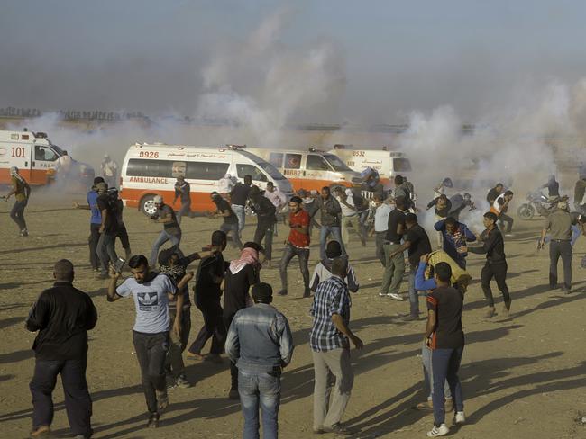 Palestinian protesters run for cover from teargas fired by Israeli troops. Picture: AP