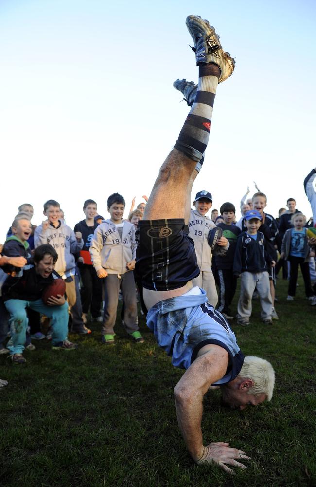 Jason Akermanis pulls his famous handstand as kids watch on at Aberfeldie.