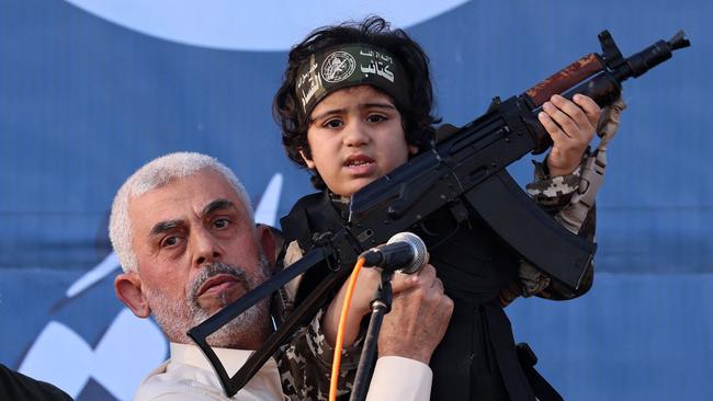 At a rally in Gaza City in 2021, Hamas leader Yahya Sinwar holds up a Kalashnikov-wielding child of an Al-Qassam Brigades fighter killed in fighting with Israel. Picture: AFP