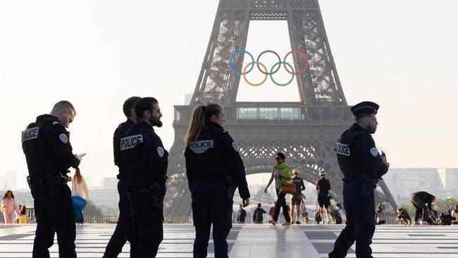 Officers of the French National Police patrol in front of the Eiffel Tower after the installation of the Olympic rings on the tower for the upcoming Paris 2024 Olympic Games, in Paris on June 7, 2024. (Photo by JOEL SAGET / AFP)