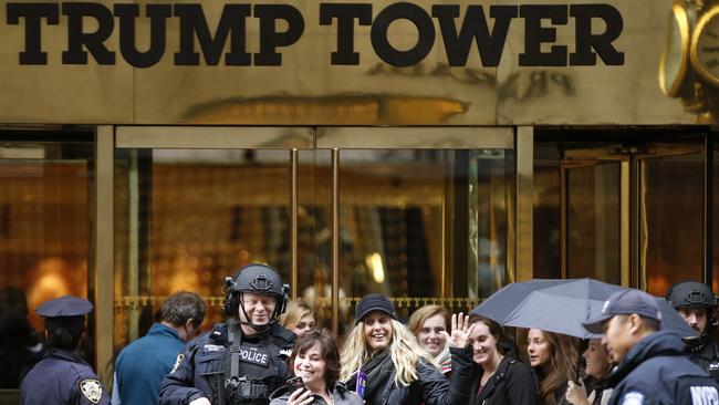 Passers-by stop for a selfie with a heavily-armed New York City police officer at the main, Fifth Avenue entrance to Trump Tower. Picture: AP Photo/Kathy Willens