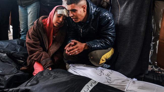 An injured girl and man mourn over the bodies of relatives killed in overnight Israeli bombardment, at the Al-Nassar hospital in Rafah in the southern Gaza Strip on February 23. Picture: Mohammed Abed/ AFP