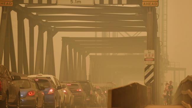 Pedestrians cross a bridge by foot as smoke haze settles over the town of Batemans Bay. Picture: Sam Mooy