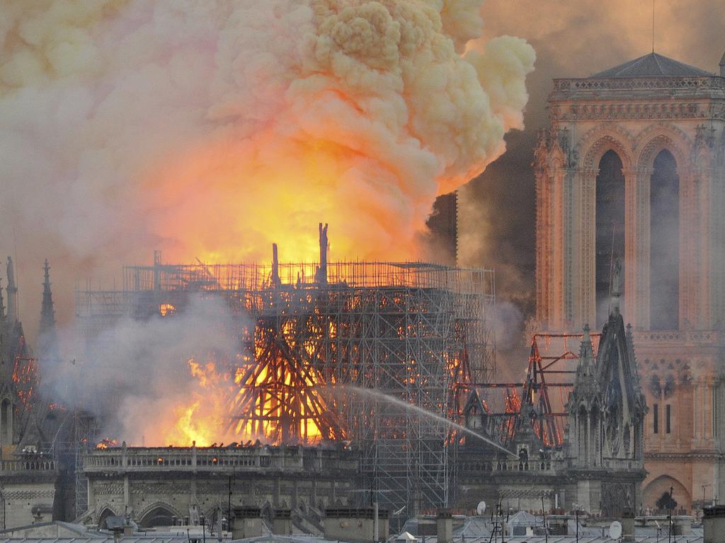 Flames and smoke rise from the blaze after the spired toppled over on Notre Dame cathedral yesterday. Picture: Thierry Mallet