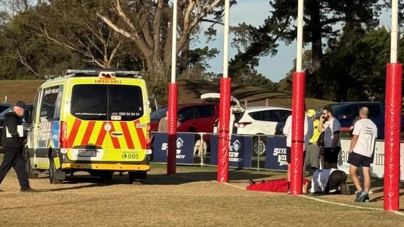 An ambulance arrives to attend Rod Young, who is on the ground covered with a red blanket.