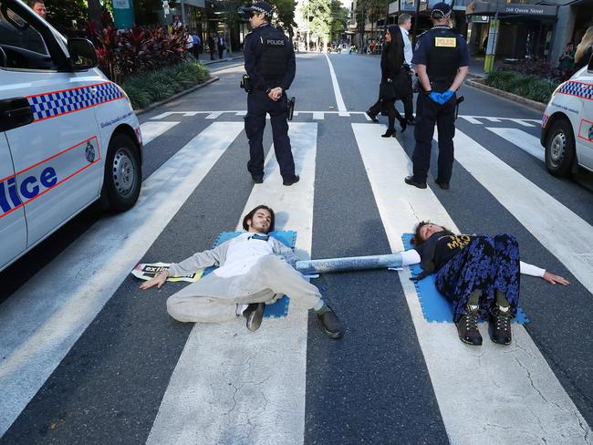 Eric Herbert and Ebony Louise Mombaerts protesting government inaction on climate change by attaching themselves to the road in Post Office Square, Brisbane, sparking a police response. Picture: Liam Kidston.