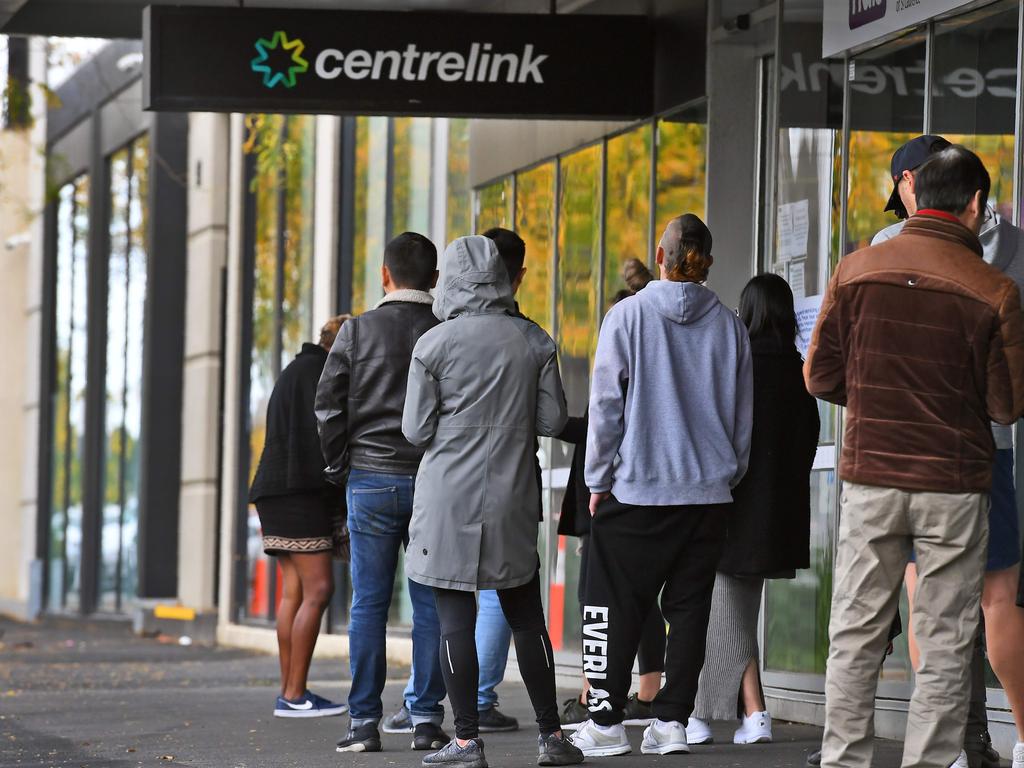 People queue up outside a Centrelink office in Melbourne on April 20, 2020, which delivers a range of government payments and services for retirees, the unemployed, families, carers and parents amongst others. - A report from the Grattan Institute predicts between 14 and 26 per cent of Australian workers could be out of work as a direct result of the coronavirus shutdown, and the crisis will have an enduring impact on jobs and the economy for years to come. (Photo by William WEST / AFP)