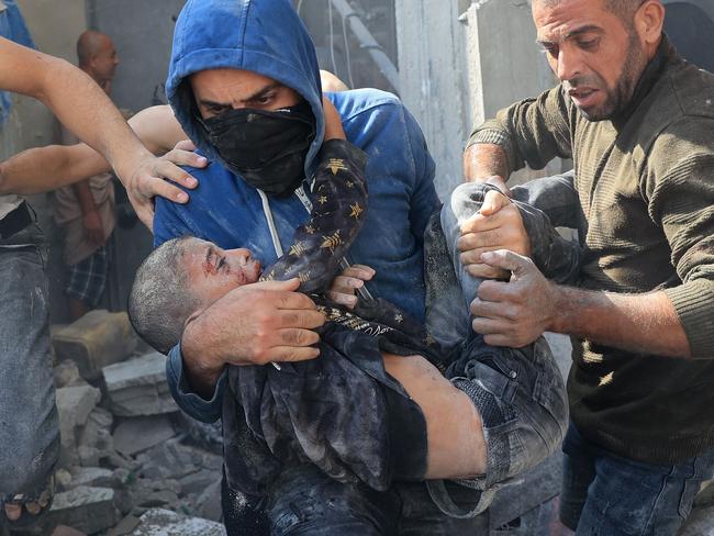 EDITORS NOTE: Graphic content / TOPSHOT - A Palestinian man carries a victim of an Israeli bombardment in Rafah in the southern Gaza Strip on November 7, 2023, amid continuing battles between Israel and the Palestinian militant group Hamas. (Photo by SAID KHATIB / AFP)