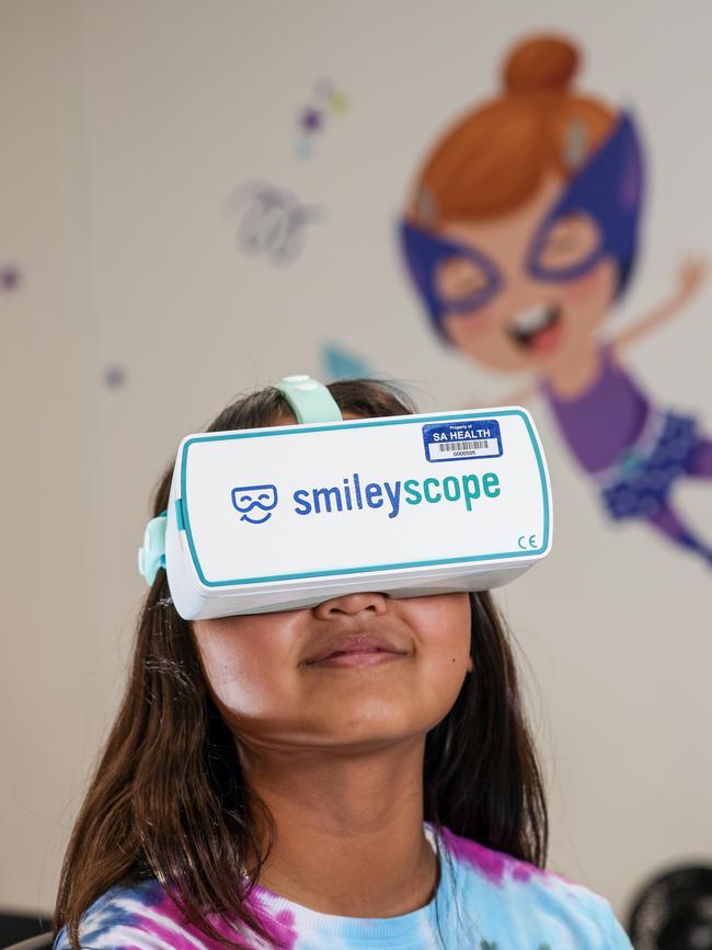 Nyomi’s sister Chloe Meth, 11, gets her turn on the Smileyscope headset ahead of being vaccinated at the Adelaide Women and Children Hospital Vaccination Clinic. Picture: Russell Millard