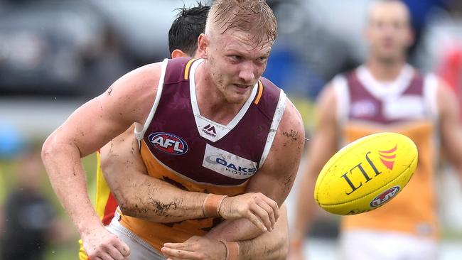 Nick Robertson of the Lions gets a handball away.