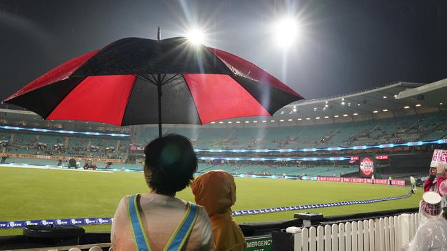 Spectators take shelter during a rain-affected BBL game in Sydney.